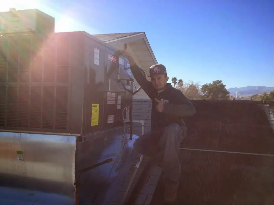 HVAC technician performing AC Tune-Up on a rooftop unit in Norco