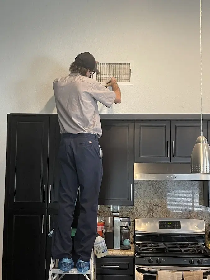 Technician inspecting an air vent during HVAC service in Norco